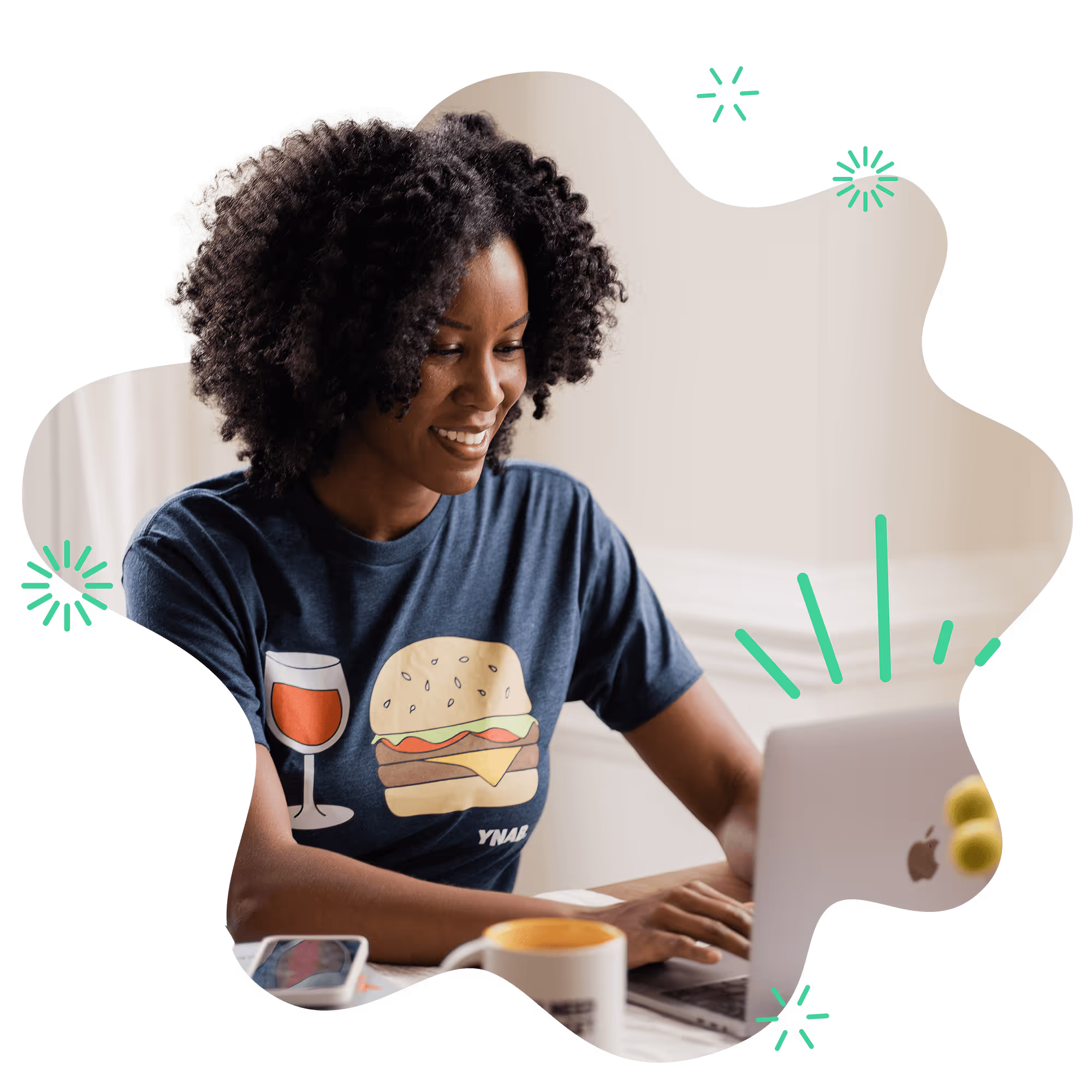 A smiling woman sitting at a table typing on a laptop